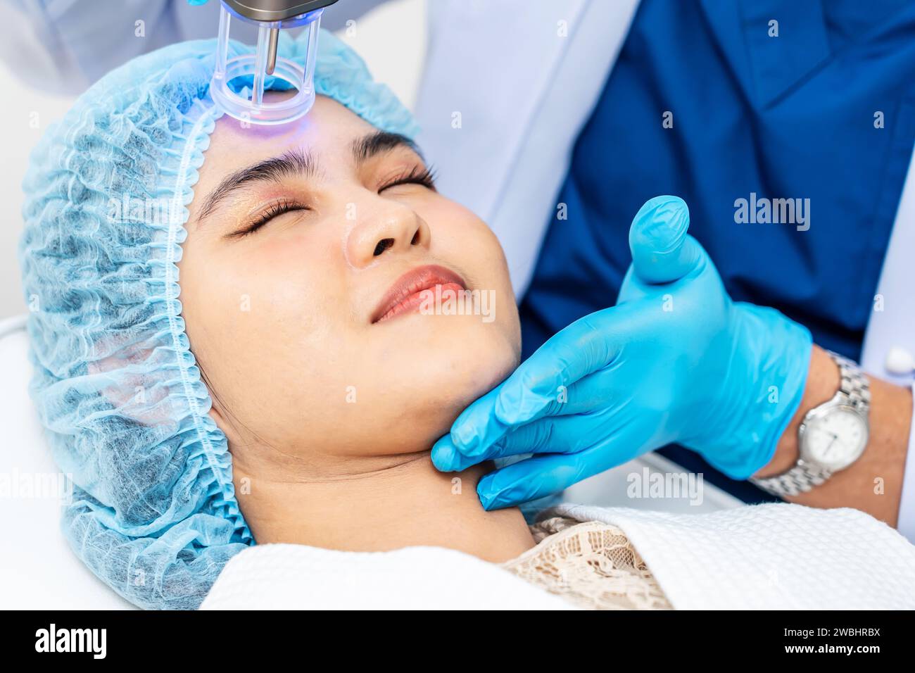 Dottore asiatico che fa laser sulla faccia della donna alla clinica di bellezza. Bella donna con trattamento viso per la cura della pelle presso la clinica di bellezza, trattamento viso anti-invecchiamento Foto Stock