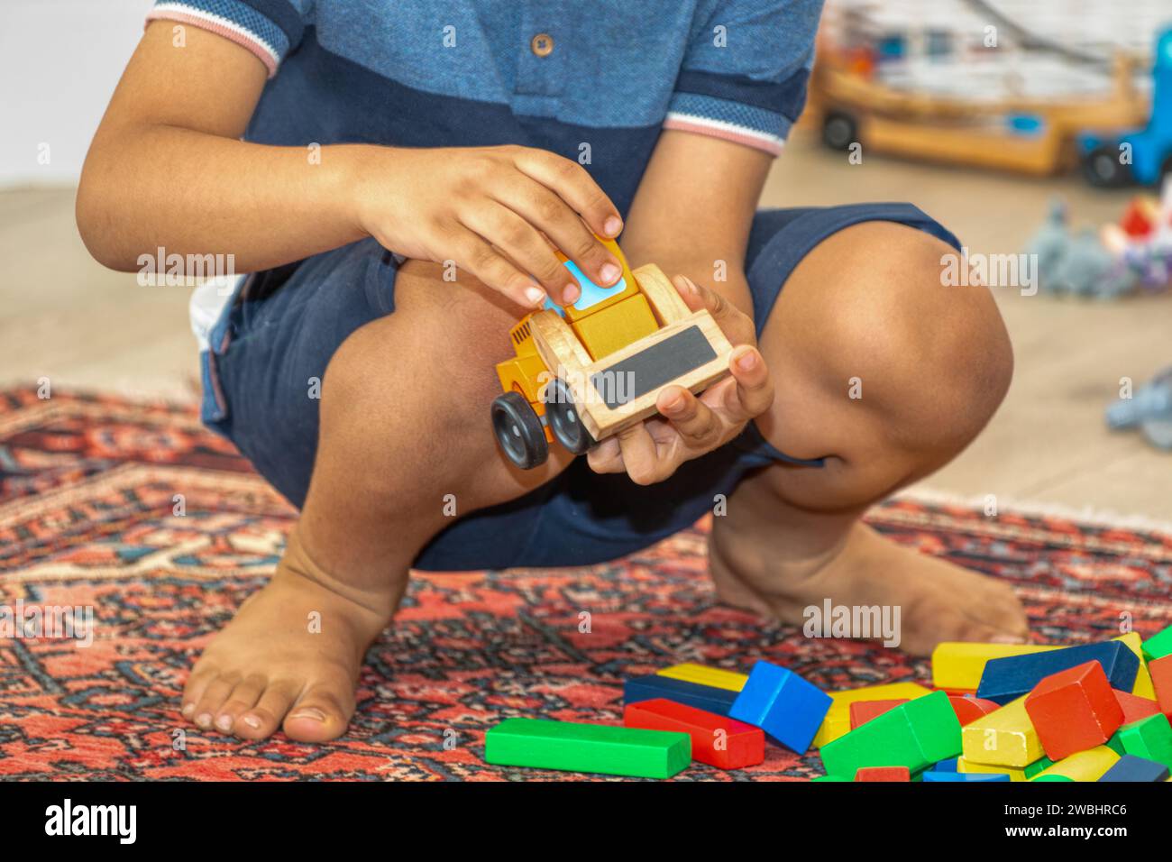 giocattoli in legno per bambini, bulldozer e cubetti colorati sulla moquette, nella stanza dei bambini Foto Stock