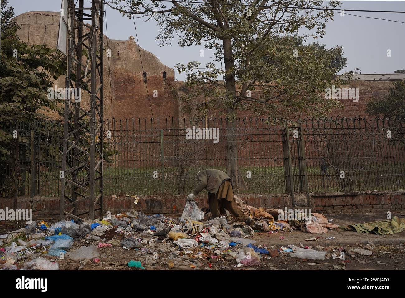 Un uomo che raccoglie rifiuti in un sito informale di smaltimento dei rifiuti fuori da una delle mura del forte di Lahore, Lahore, Pakistan Foto Stock