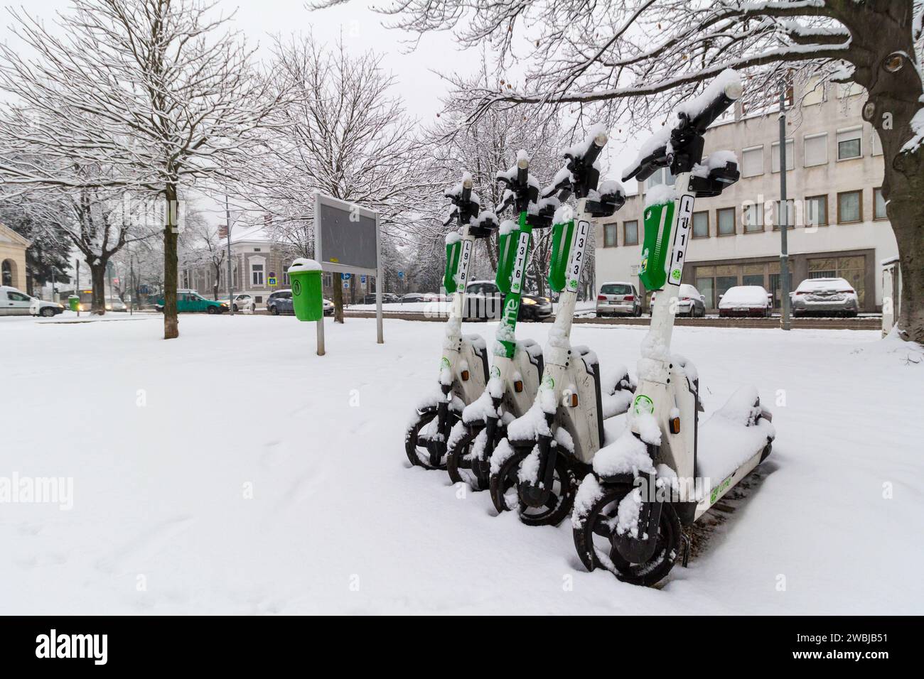 Neve fresca d'inverno, scooter elettrici AL LIME in fila per strada, Sopron, Ungheria Foto Stock