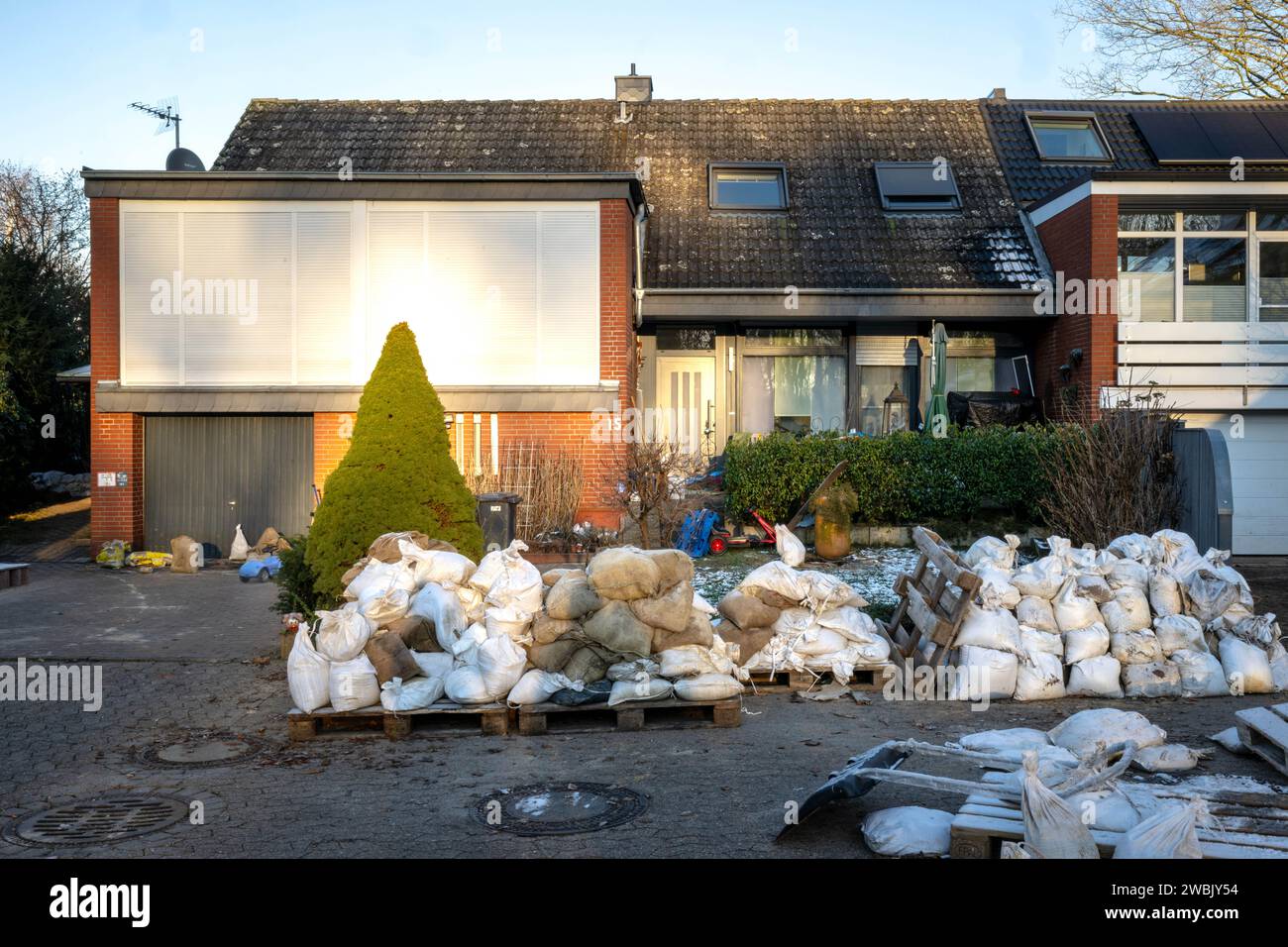 Lilienthal, Germania. 10 gennaio 2024. Sacchi di sabbia e rifiuti voluminosi davanti alle case colpite dalle inondazioni. Il comune di Lilienthal, vicino a Brema, è stato gravemente colpito dalle inondazioni fin da Natale. Dozzine di case e appartamenti furono evacuati e altre case furono temporaneamente prive di elettricità o gas. Le acque alluvionali stanno ora diminuendo e la situazione si sta attenuando. Molti residenti hanno iniziato a ripulire. (A dpa-KORR "ripulire dopo le inondazioni - "come gestiremo?") Crediti: Sina Schuldt/dpa/Alamy Live News Foto Stock