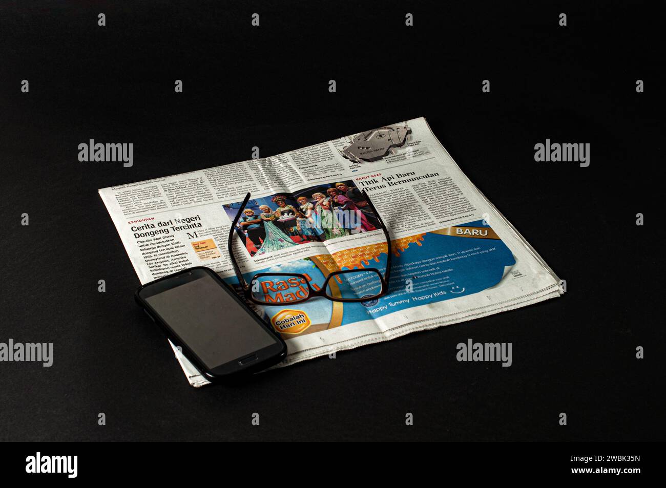 pile di giornali da leggere per notizie e informazioni finanziarie e occhiali per una maggiore chiarezza, fotografati su uno sfondo scuro Foto Stock
