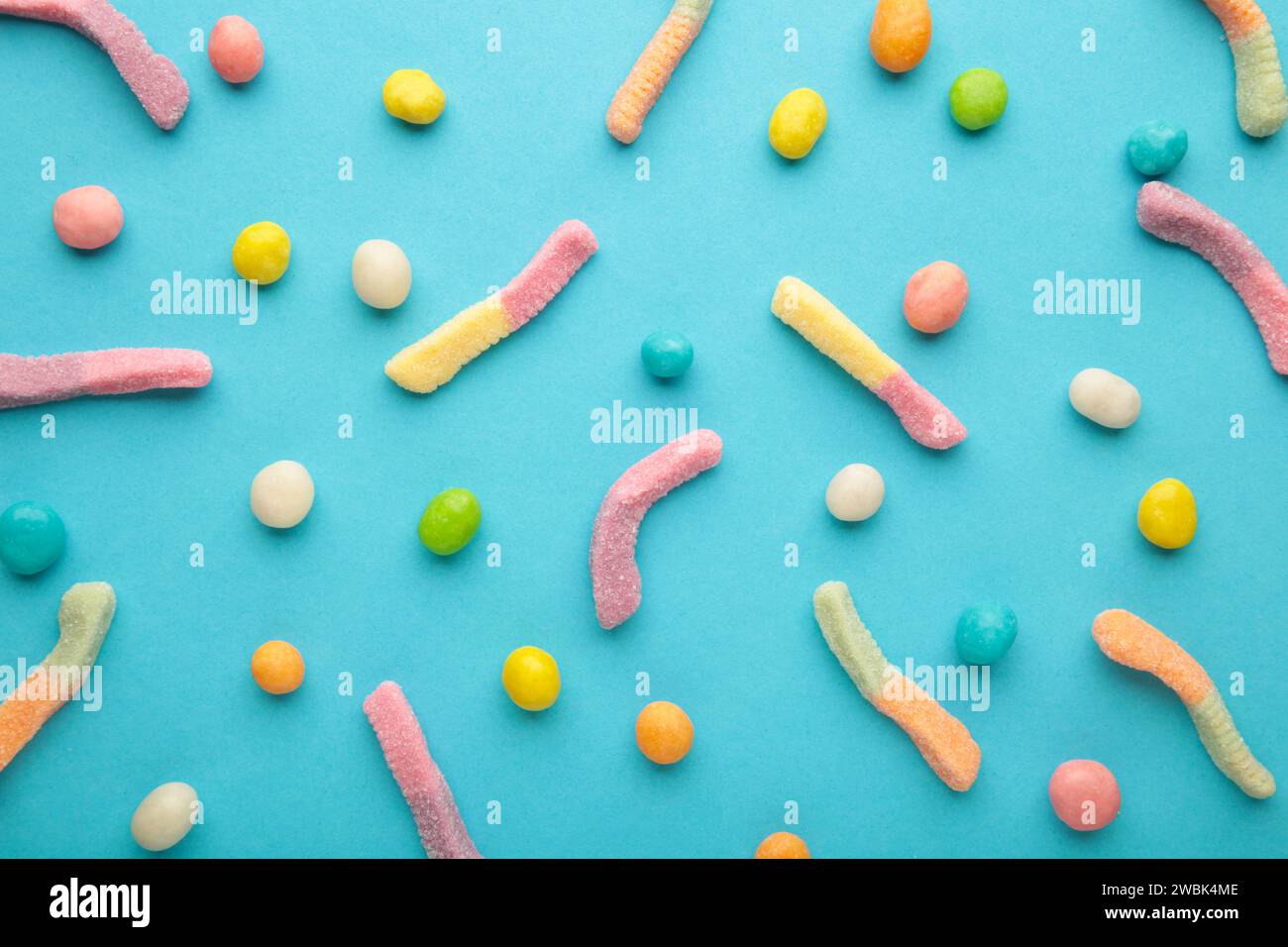 Caramelle di vermi gommosi e pillole su sfondo blu. Vista dall'alto Foto Stock