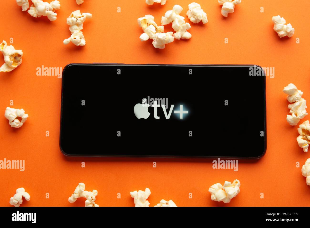 Nikolaev, Ucraina - 20 novembre 2021. Smartphone con logo Apple TV e popcorn su sfondo arancione. Vista dall'alto Foto Stock