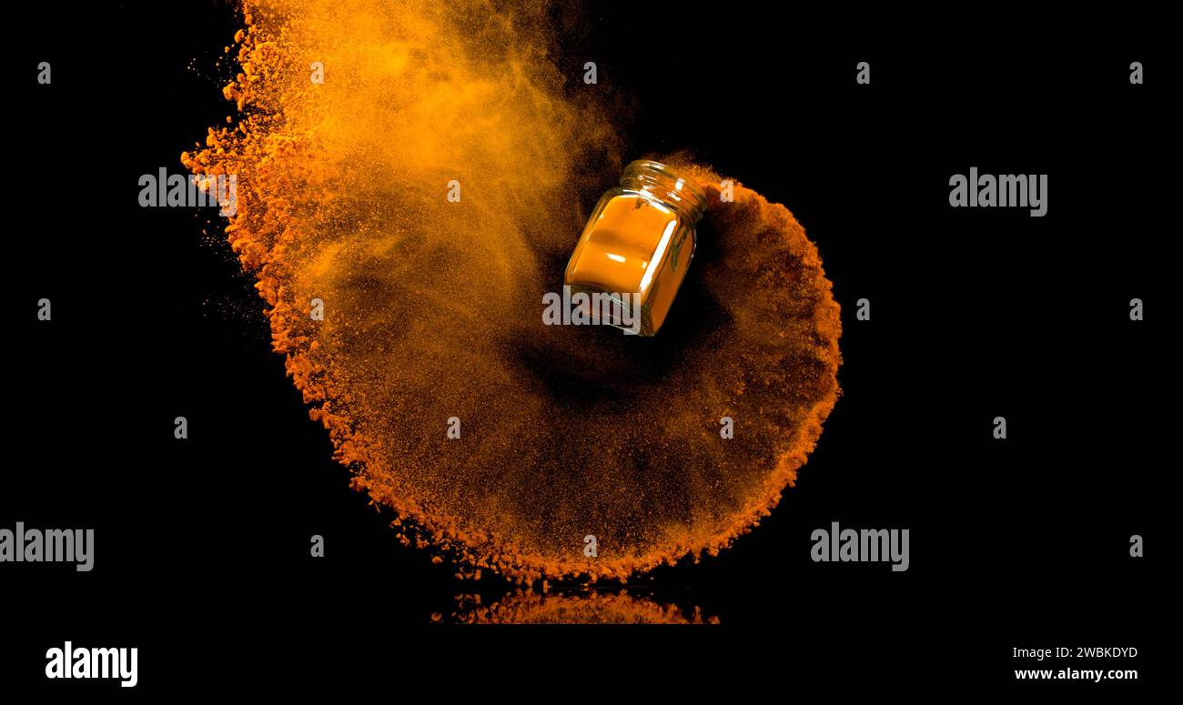 Curcuma, curcuma longa, polvere in un piccolo barattolo che cade su sfondo nero, Indian Spice Foto Stock