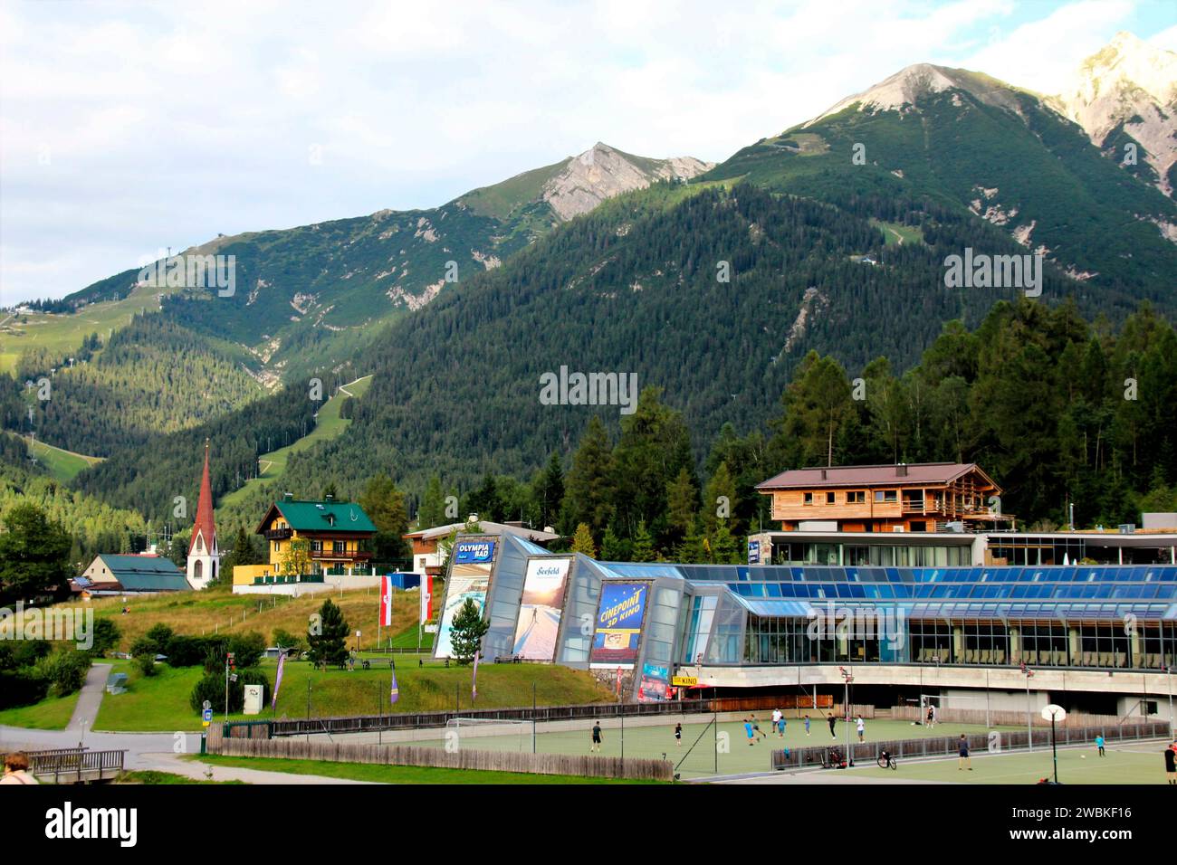 Austria, Tirolo, Seefeld, vista sulla città, centro congressi, campo da tennis, campo da pallavolo, centro ricreativo, piscina, sauna, alto Adige, gente, sport, vacanze, vacanze estive, costruzione di eventi, vista sulle montagne, Alpi, Reitherspitze all'estrema destra, Seefelderspitze a sinistra, destinazione, turismo Foto Stock