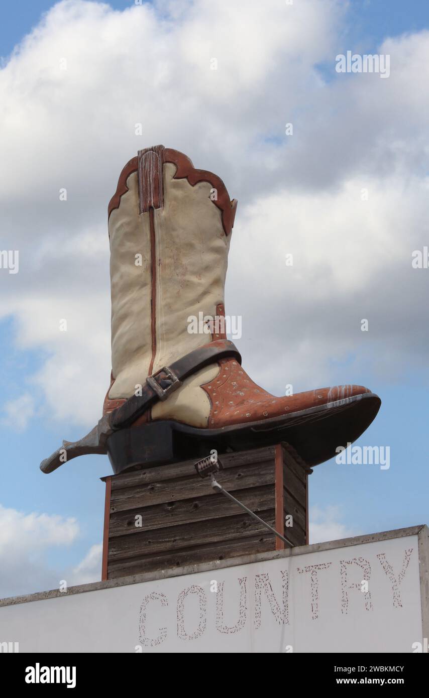 Stivali da cowboy giganti su Sign of Abandoned Business, situati nella zona rurale del Texas. Weir Texas Foto Stock