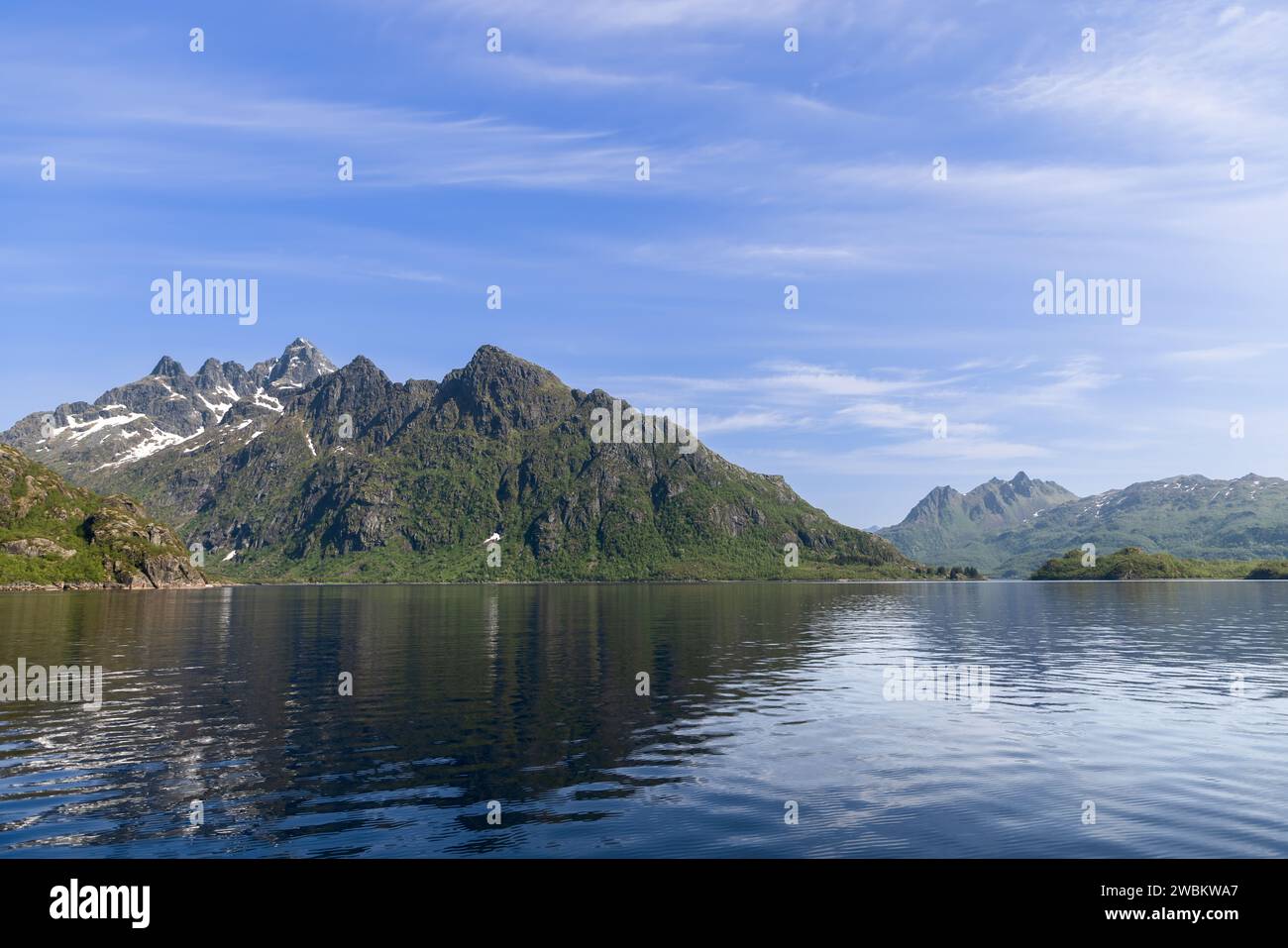 Le acque calme rispecchiano il suggestivo paesaggio montano di Lofoten, Norvegia, inondato alla luce di una luminosa giornata estiva Foto Stock