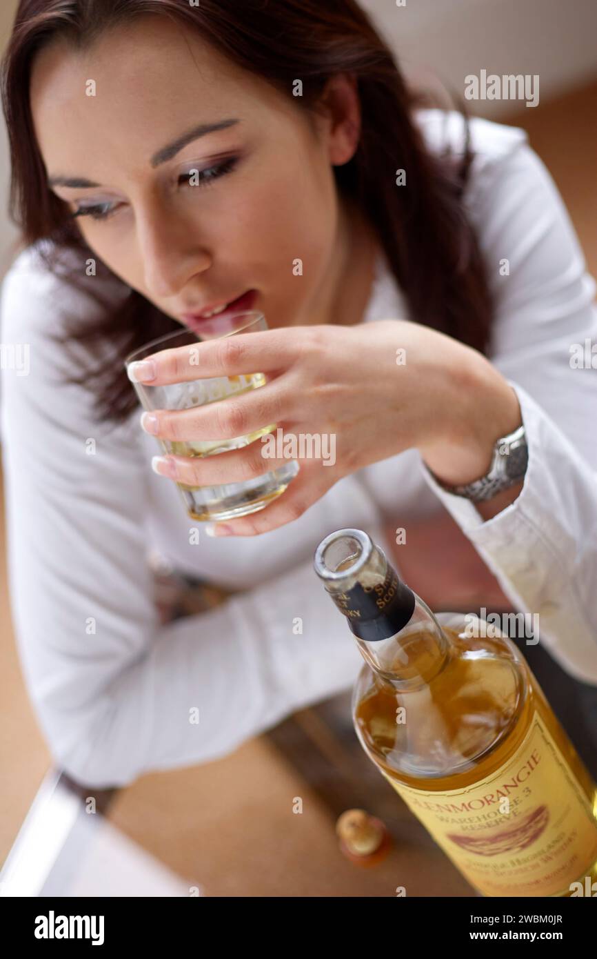 Donna che beve un bicchiere di Whisky Foto Stock