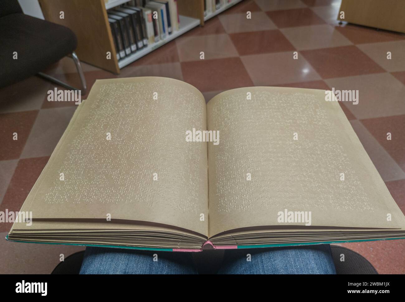 Un uomo cieco che legge un libro in braille in biblioteca. Scatto del punto di vista Foto Stock