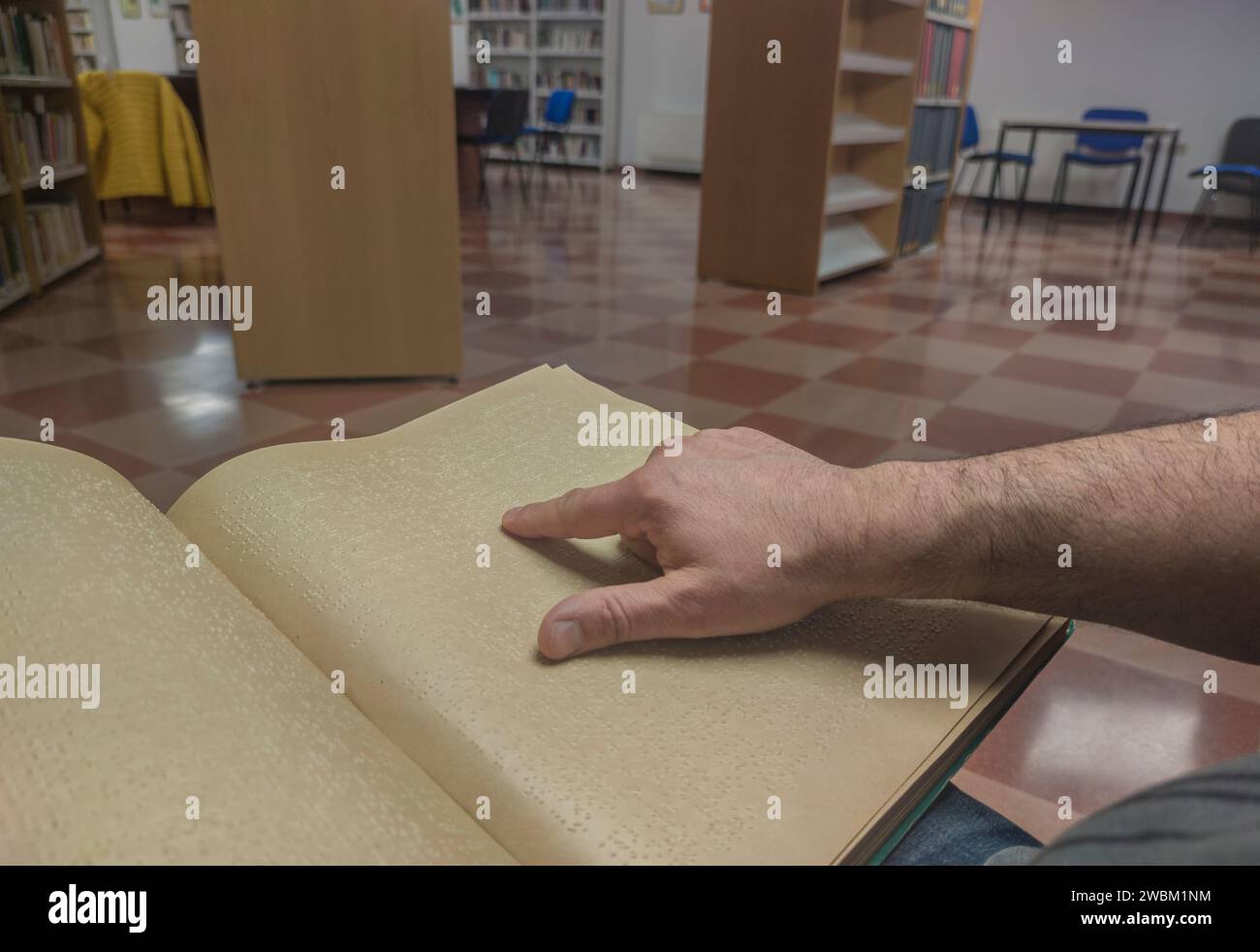 Un uomo cieco che legge un libro in braille in biblioteca. Scatto del punto di vista Foto Stock