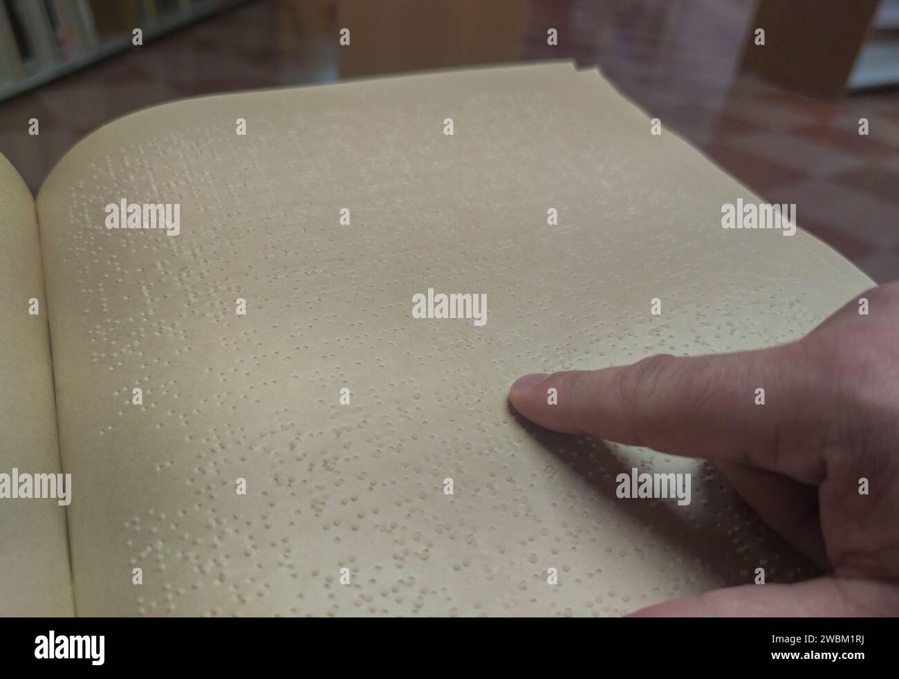 Un uomo cieco che legge un libro in braille in biblioteca. Messa a fuoco selettiva Foto Stock