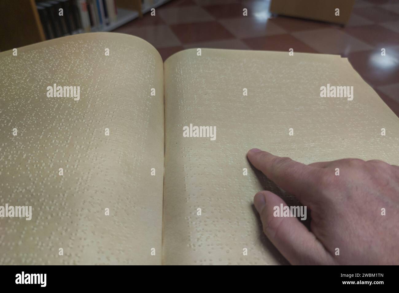 Un uomo cieco che legge un libro in braille in biblioteca. Messa a fuoco selettiva Foto Stock