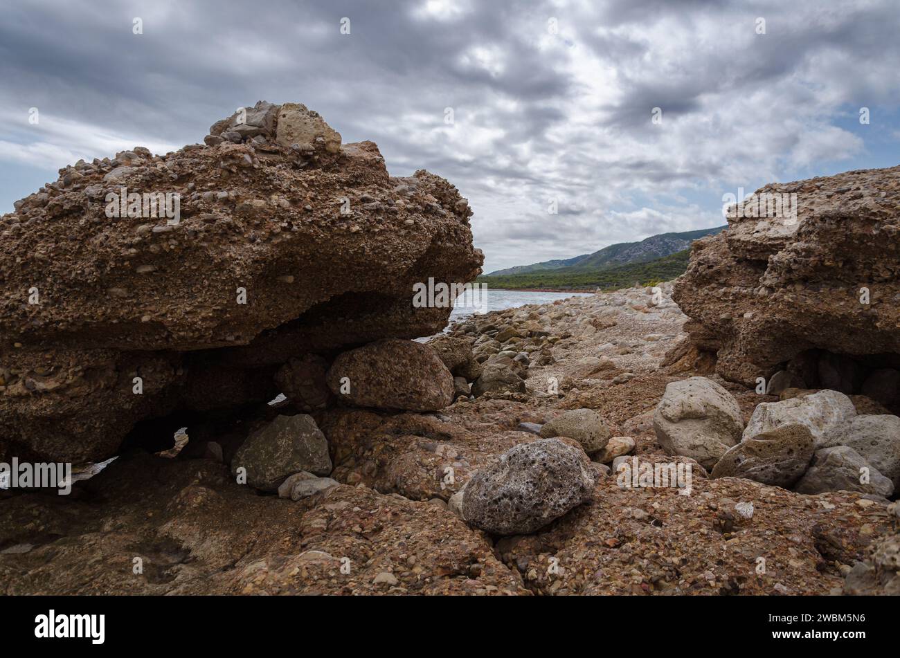 Solitaria spiaggia rocciosa mediterranea nel Parco naturale della Sierra de Irta sotto un cielo nuvoloso e tempestoso, Castellon, Spagna Foto Stock