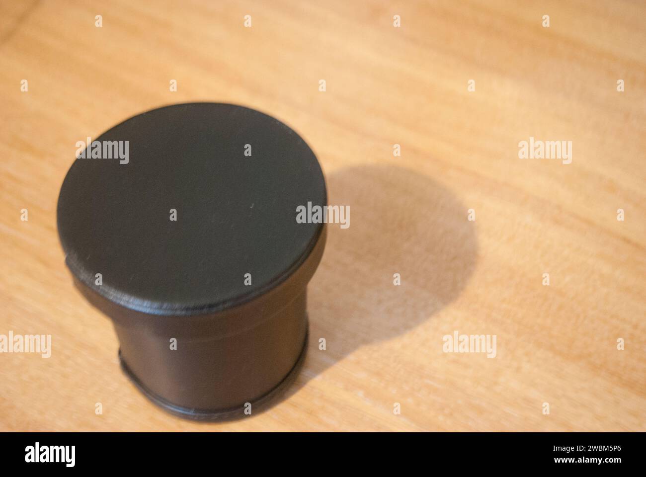 Tazza con dadi neri, con coperchio, su scrivania di legno Foto Stock