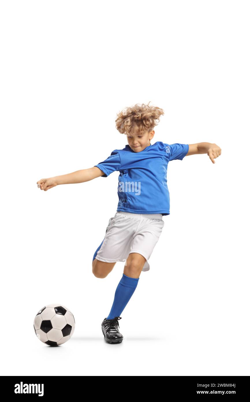 Ragazzo con una divisa da calcio che calci una palla isolata su sfondo bianco Foto Stock