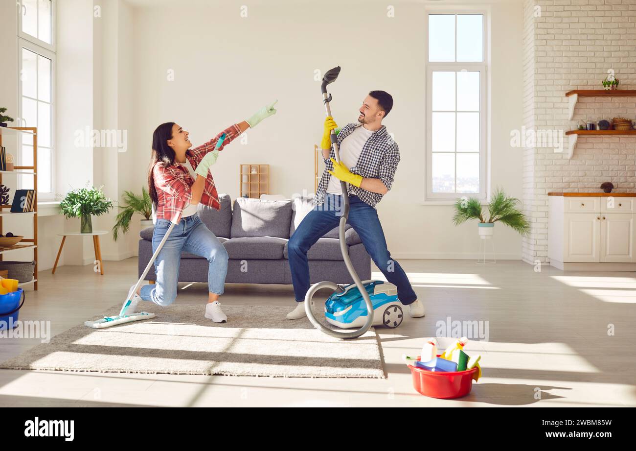 Simpatiche coppie che puliscono casa insieme divertendosi, ballando a casa mentre lavorano al lavoro Foto Stock