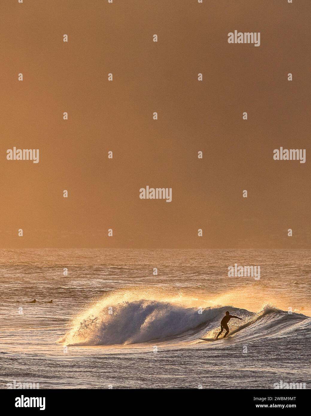 Un surfista cattura un'onda sullo sfondo dorato di ho'okipa Beach, una testimonianza dell'eredità di Maui nel surf. Foto Stock