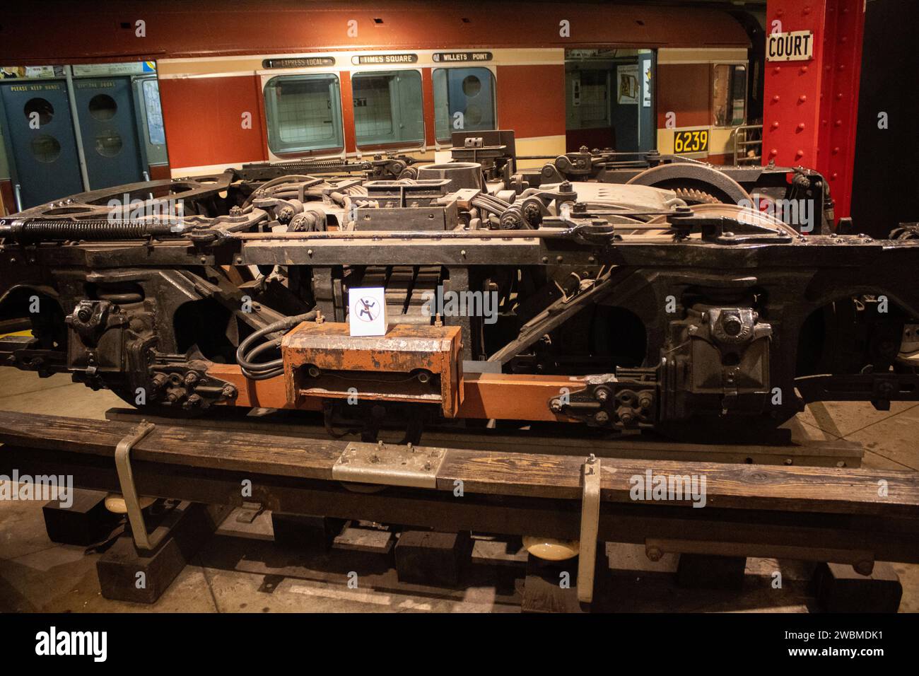Un treno passeggeri antiquato è parcheggiato accanto ad altre locomotive in un magazzino abbandonato, evocando un'aria nostalgica del passato Foto Stock