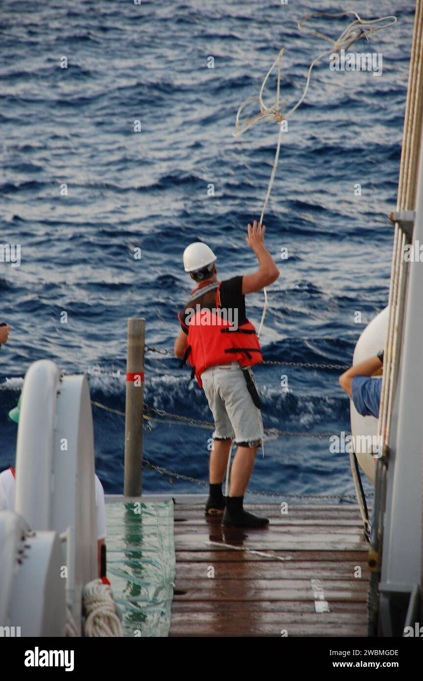 Un membro dell'equipaggio a bordo della nave di recupero della NASA Freedom Star lancia una linea di traino per catturare il cappuccio di lancio del razzo solido sinistro nell'Oceano Atlantico dopo il lancio dello Space Shuttle Discovery STS-133 dal Kennedy Space Center. Foto Stock