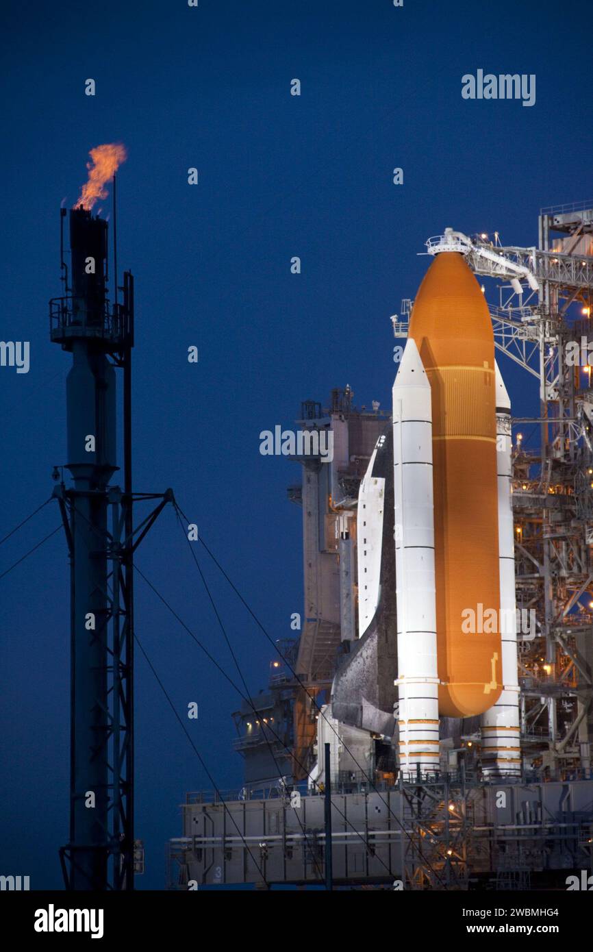CAPE CANAVERAL, Ban. Lo Space Shuttle Atlantis viene rivelato sul Launch Pad 39A al Kennedy Space Center della NASA in Florida, bagnato da luci allo xeno a seguito dello spostamento della struttura di servizio rotante (RSS). La struttura fornisce protezione contro le intemperie e l'accesso alla navetta mentre attende il decollo sulla piattaforma. La torre a sinistra viene utilizzata per bruciare in sicurezza l'idrogeno in eccesso mentre lo shuttle è sul pad prima del lancio. La retrazione dell'RSS segna una pietra miliare nel conto alla rovescia della missione STS-135 di Atlantis. Atlantis e il suo equipaggio di quattro persone; il comandante Chris Ferguson, il pilota Doug Hurley, Mission specialis Foto Stock