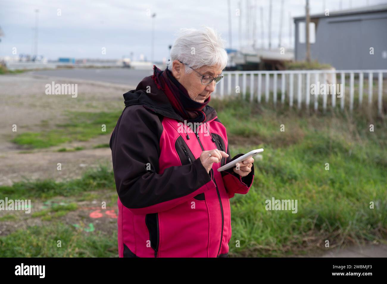 Ritratto di una donna anziana che invia messaggi sul suo smartphone all'aperto Foto Stock