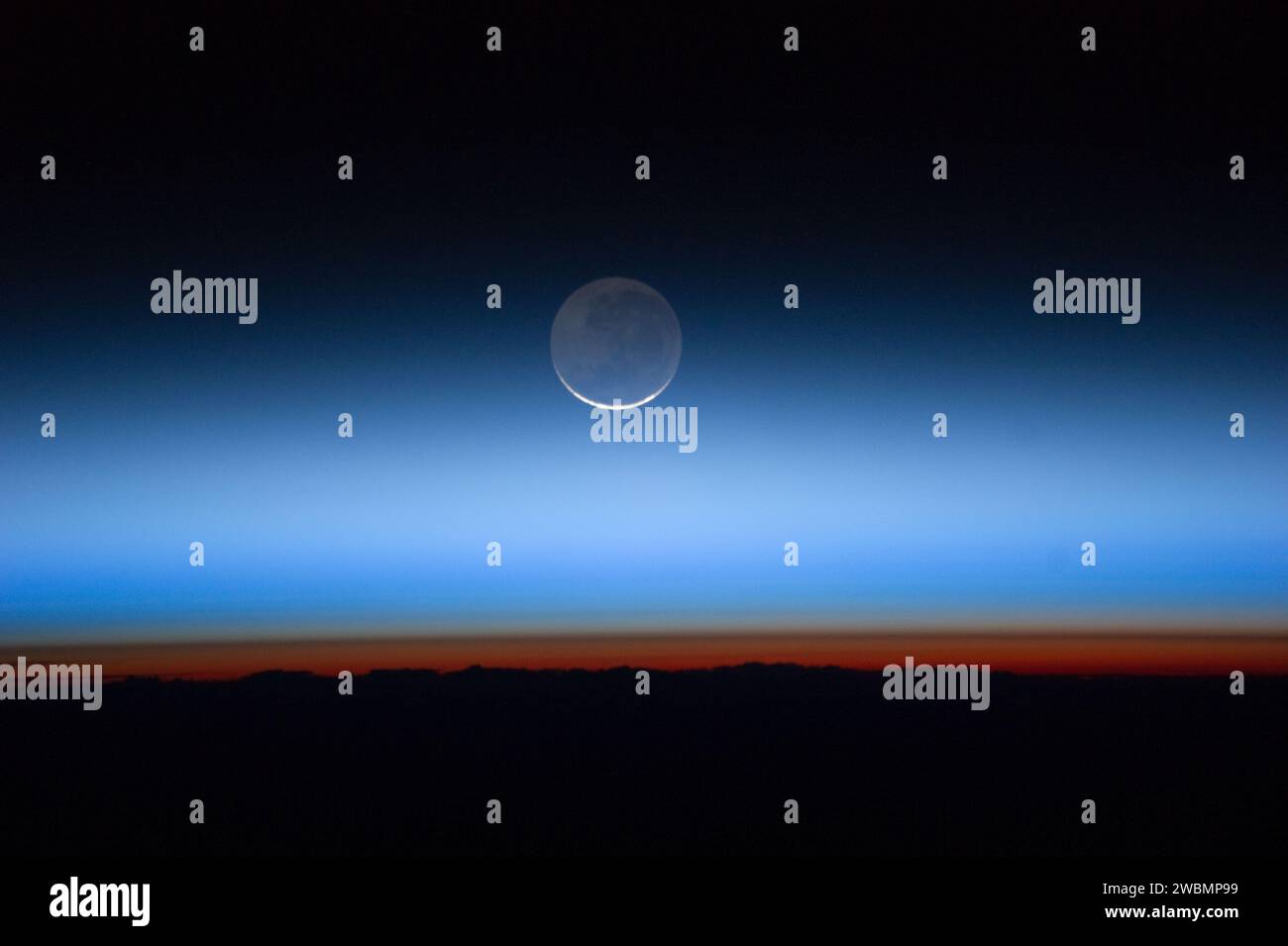 ISS028-e-020073 (31 luglio 2011) --- fotografata da un membro dell'equipaggio della Expedition 28 a bordo della stazione spaziale Internazionale, questa immagine mostra la luna al centro, con l'arto della Terra vicino al fondo che passa nella troposfera di colore arancione, la parte più bassa e densa dell'atmosfera terrestre. La troposfera termina bruscamente in corrispondenza della tropopausa, che appare nell'immagine come il confine nitido tra l'atmosfera di colore arancione e blu. Le nubi color nocciola argenteo si estendono ben al di sopra della troposfera terrestre. Foto Stock