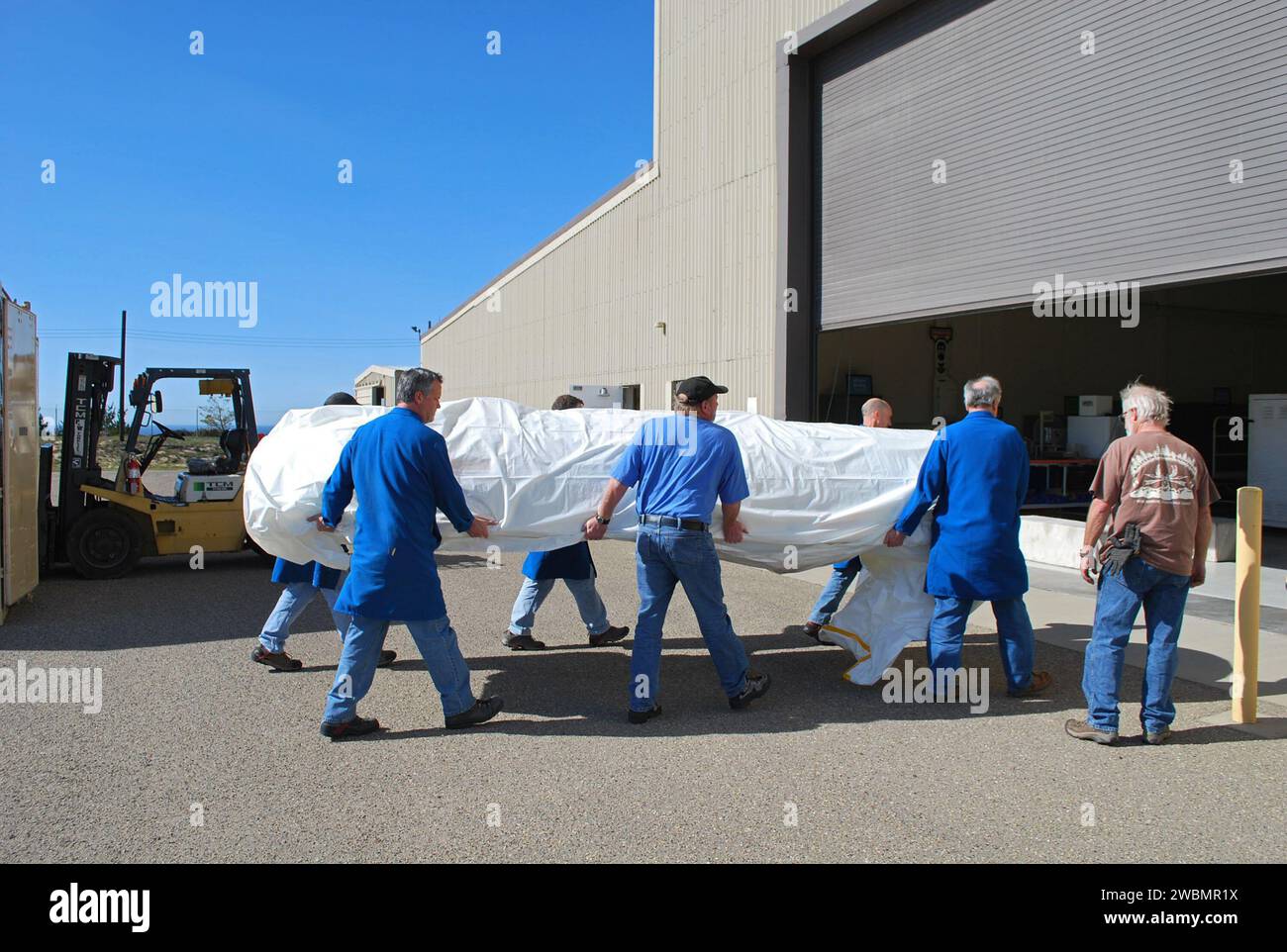 Alla Vandenberg Air Force base, i lavoratori scaricano le metà della carena del razzo Pegasus XL per la navicella NuSTAR. La carenatura viene elaborata in una stanza pulita prima che il razzo e la navicella siano portati all'atollo di Kwajalein per il lancio. NuStar mapperà buchi neri, materiale radioattivo nei resti di supernova, raggi cosmici e studierà la fisica estrema intorno alle stelle collassate. Foto Stock