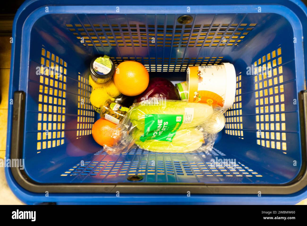 Vista dall'alto guardando verso il basso alcuni prodotti alimentari nel cestino della spesa in plastica blu al supermercato Lidl, coda alla cassa, 2024 UK KATHY DEWITT Foto Stock