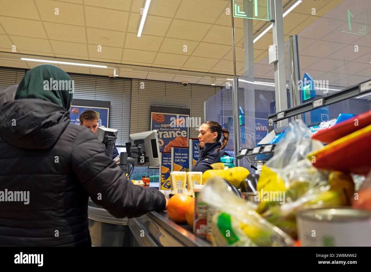 Giovane dipendente che lavora al cibo fino al banco cassa del supermercato Lidl, 2024 Regno Unito, KATHY DEWITT Foto Stock