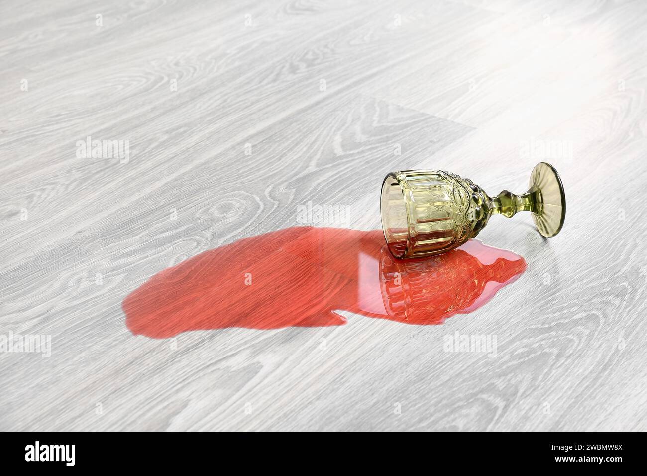 Pavimento in laminato di legno con bicchiere di vino rovesciato Foto Stock