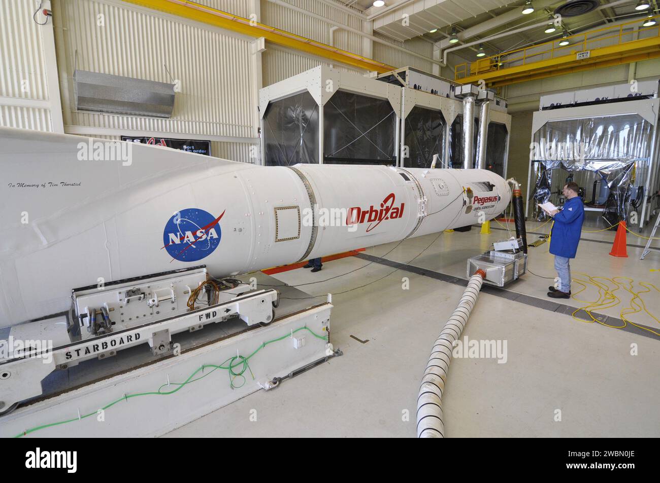 Un tecnico ispeziona il razzo Pegasus XL con il telescopio a raggi X NuSTAR della NASA all'interno dell'hangar di Orbital presso la Vandenberg Air Force base prima di essere spostato su un trasportatore alla pista per l'attacco a un aereo L-1011 per il lancio per studiare buchi neri e raggi cosmici. Foto Stock