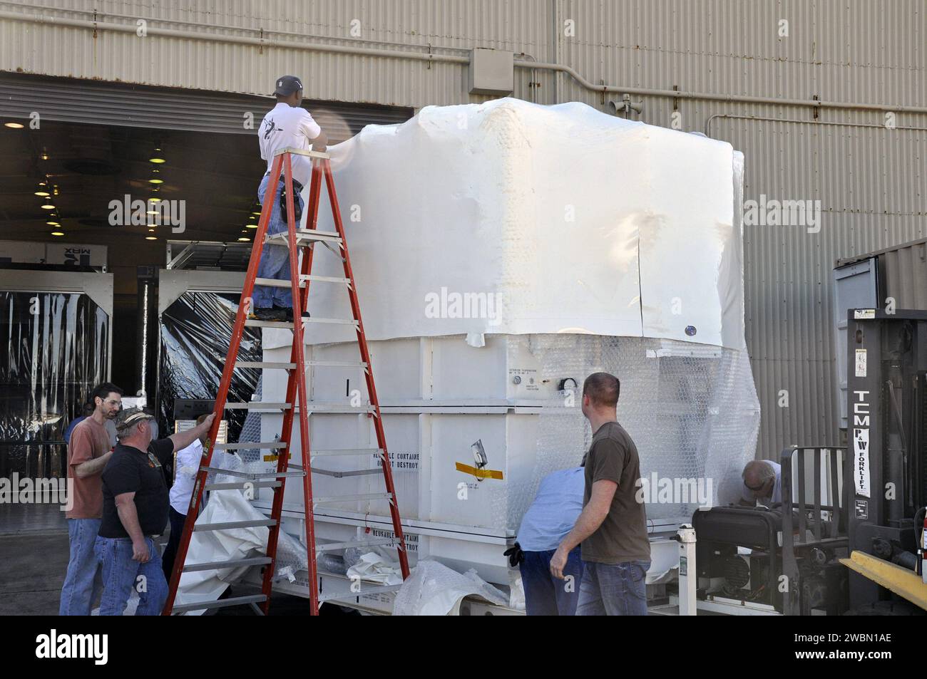 I lavoratori della Vandenberg Air Force base rimuovono la navicella NuSTAR della NASA dal suo contenitore di spedizione controllato dall'ambiente in preparazione dell'integrazione con il razzo Pegasus XL per un lancio programmato a marzo. Foto Stock