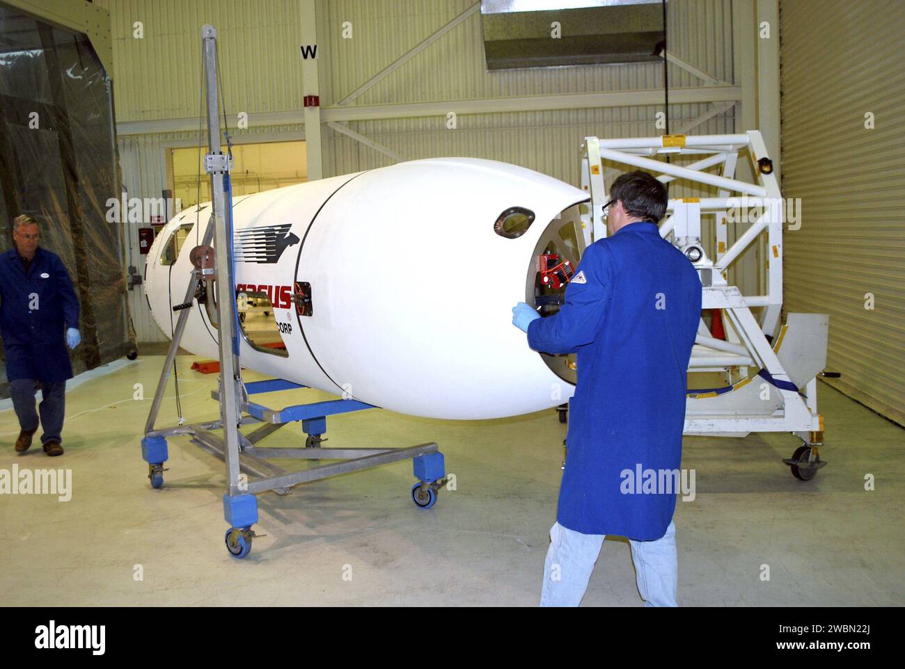 Un tecnico della Vandenberg Air Force base, California, sposta una sezione della carenatura del veicolo spaziale NuSTAR verso una camera bianca. La carenatura proteggerà il telescopio durante la salita su un razzo Pegasus XL. Dopo l'elaborazione, il razzo e la navicella spaziale saranno portati all'atollo di Kwajalein per il lancio. NuStar studierà i buchi neri, i resti di supernova, i raggi cosmici e la fisica delle stelle collassate. Foto Stock