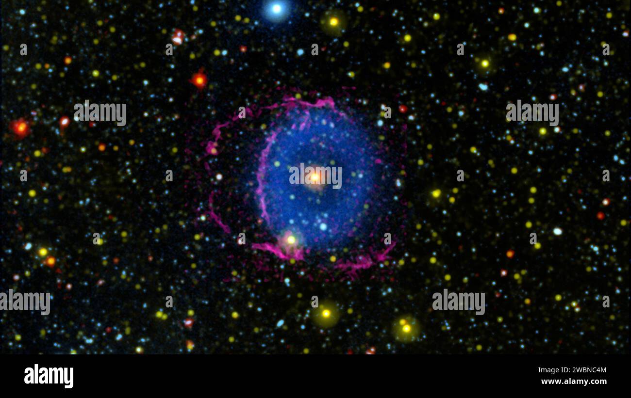 La nebulosa ad anello blu è stata scoperta nel 2004 dalla missione Galaxy Evolution Explorer (GALEX) della NASA. Gli astronomi pensano che la nebulosa sia stata creata dalla fusione di due stelle, e che stiamo vedendo il sistema qualche migliaio di anni dopo la fusione, quando le prove della collisione sono ancora evidenti. La luce blu nell'immagine mostra la nube di detriti creata dalla fusione. Quando la nuvola calda di materiale si espanse nello spazio e si raffreddò, formò molecole di idrogeno che si scontrarono con il mezzo interstellare (le particelle che occupano lo spazio tra le stelle). Queste collisioni causarono le molecole di idrogeno t Foto Stock