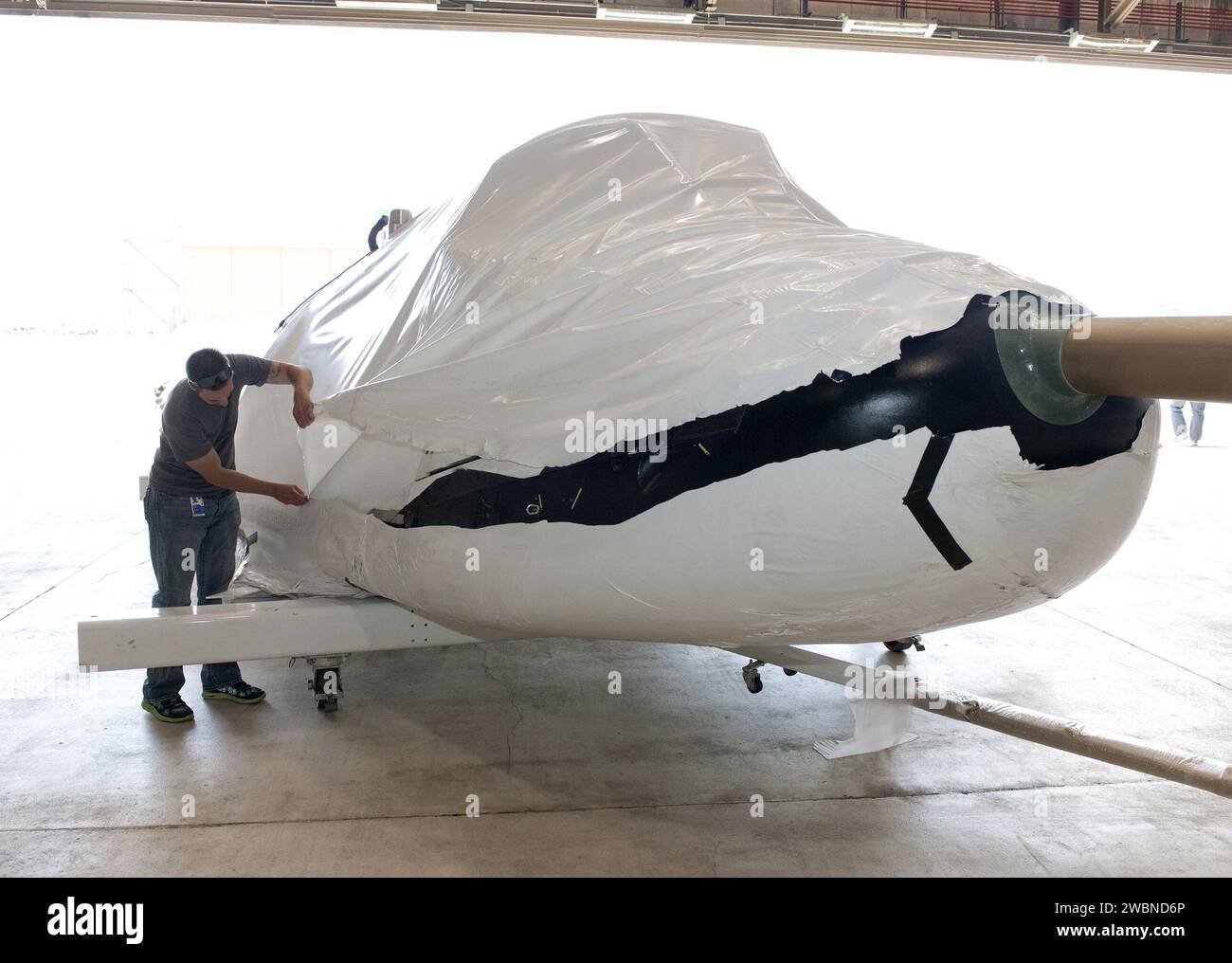 Il veicolo di prova SNC Dream Chaser arriva al Dryden Flight Research Center della NASA a Edwards, California. L'involucro protettivo in plastica viene rimosso dal dipendente SNC Jason Dixon. Il veicolo sarà sottoposto a test di volo a terra e di avvicinamento e atterraggio nell'ambito del Commercial Crew Program della NASA nell'ambito dell'iniziativa CCiCap per lo sviluppo di servizi commerciali di volo umano. Foto Stock