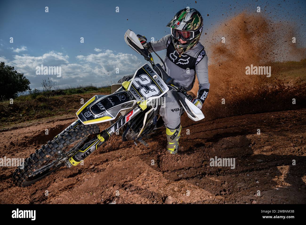 Pilota di motocross in azione con velocità sulla telecamera con grandangolo e sollevamento di fango, rocce e sporcizia. Foto Stock