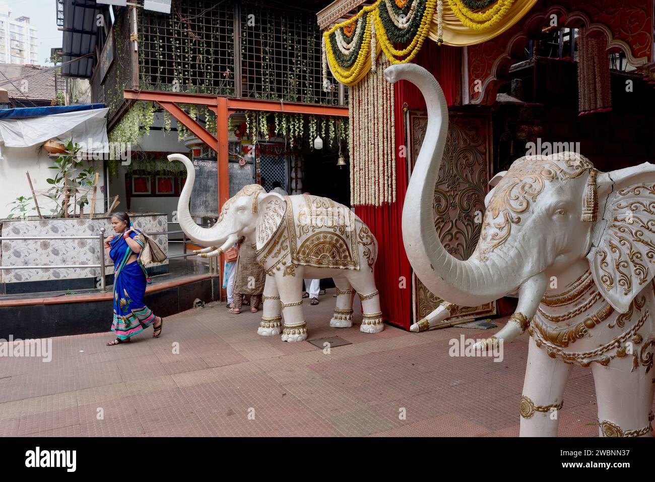 Due statue di elefanti con tronchi rialzati accolgono i visitatori all'ingresso di una sala festival indù a Panjrapole, Bhuleshwar, Mumbai, India Foto Stock