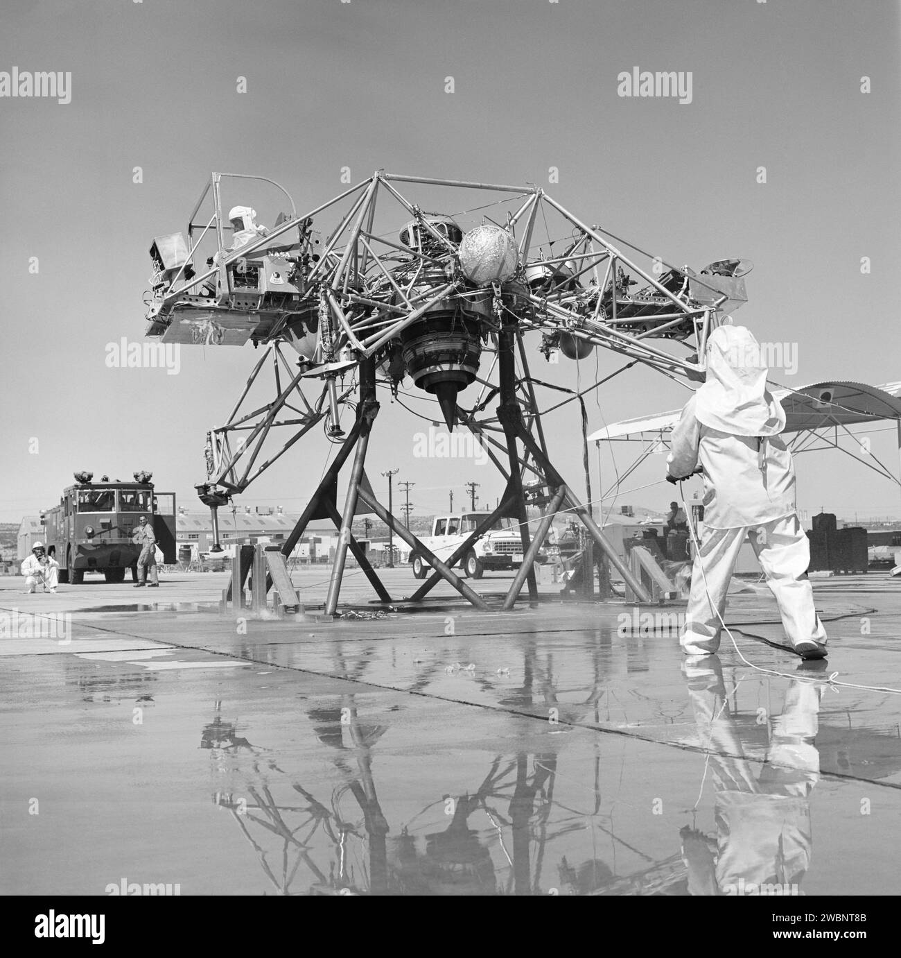 I meccanici dell'Armstrong Flight Research Center della NASA indossavano tute antincendio mentre lavoravano al Lunar Landing Research Vehicle, che utilizzava propulsori di perossido di idrogeno puro al 90% per simulazioni di addestramento all'atterraggio sulla luna degli astronauti. Foto Stock