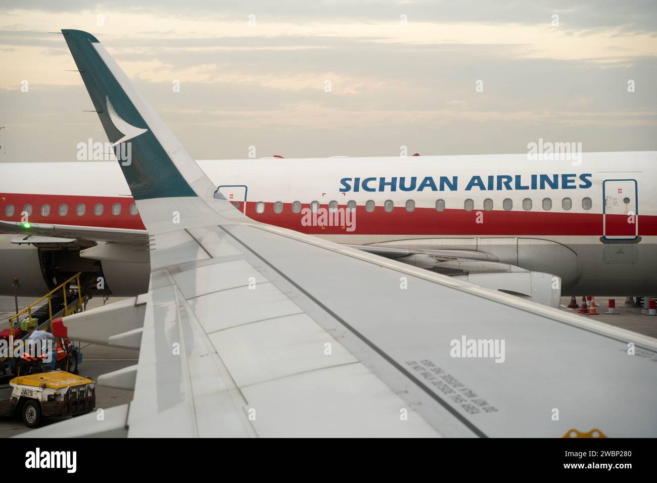 L'aereo della Sichuan Airlines visto da Cathay Pacific attraverso le sue ali all'Aeroporto Internazionale di Hong Kong, Cina Foto Stock