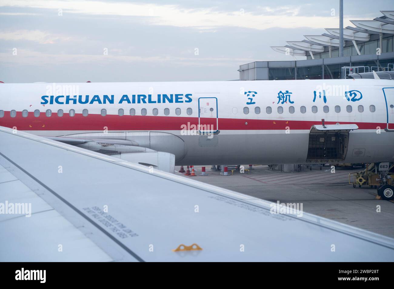 L'aereo della Sichuan Airlines visto da Cathay Pacific attraverso le sue ali all'Aeroporto Internazionale di Hong Kong, Cina Foto Stock