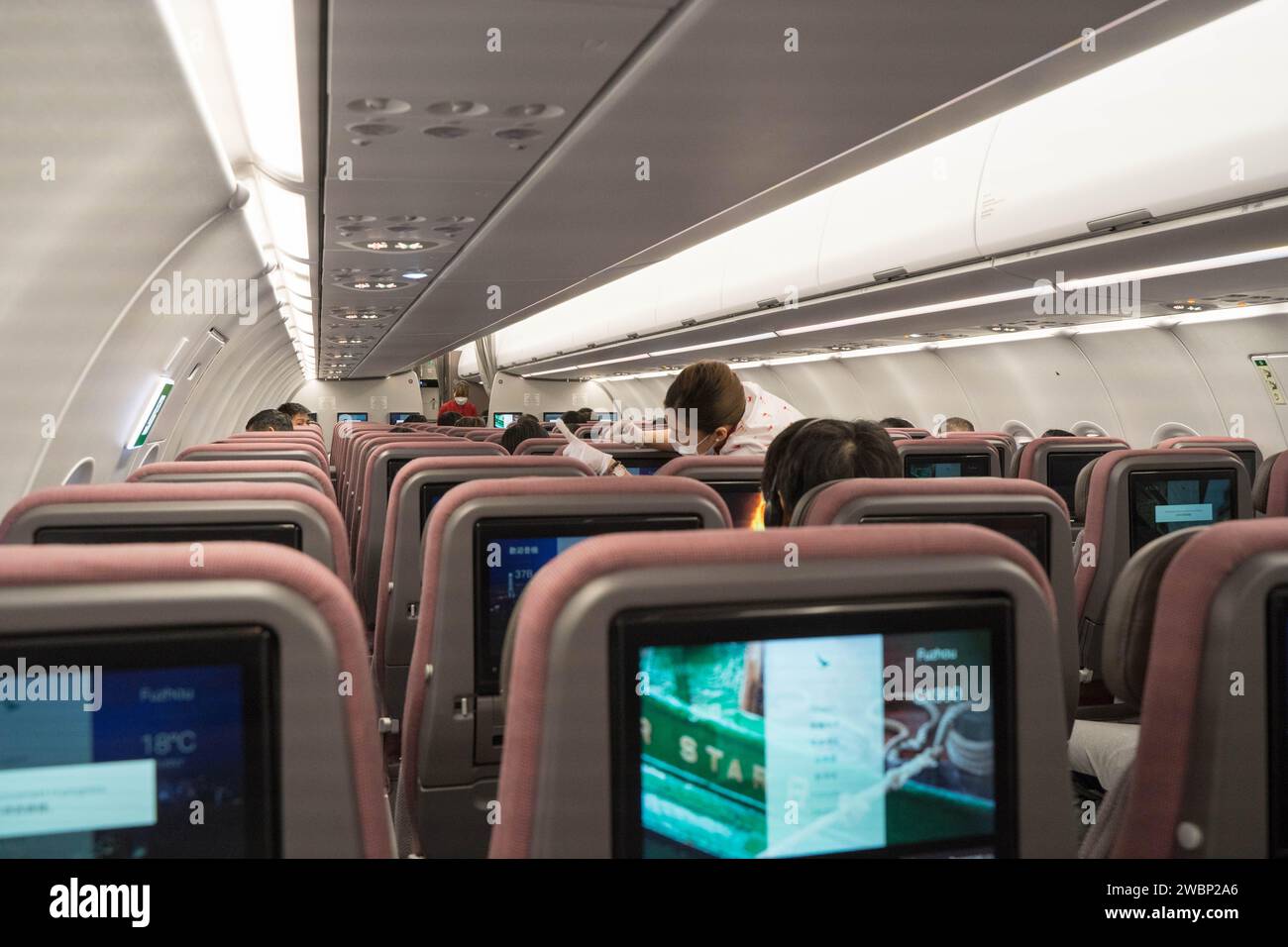 Vista dell'interno di un aereo dove una hostess si trovava nella corsia aiutava un passeggero, Hong Kong Cina. Foto Stock