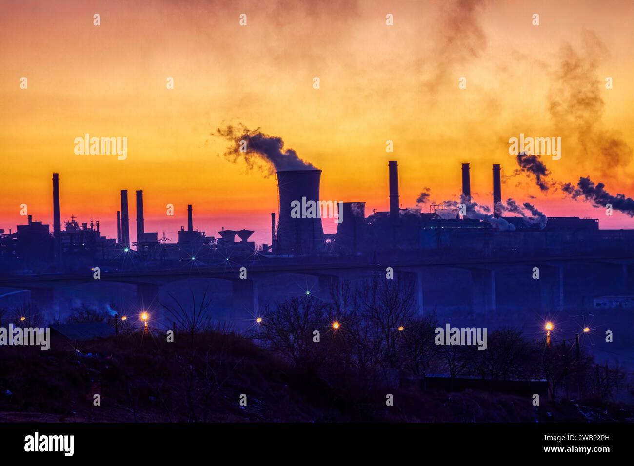 fabbrica di acciaio al tramonto che causa inquinamento fumo, problema di riscaldamento globale che causa problemi ambientali, vista sul ponte Foto Stock