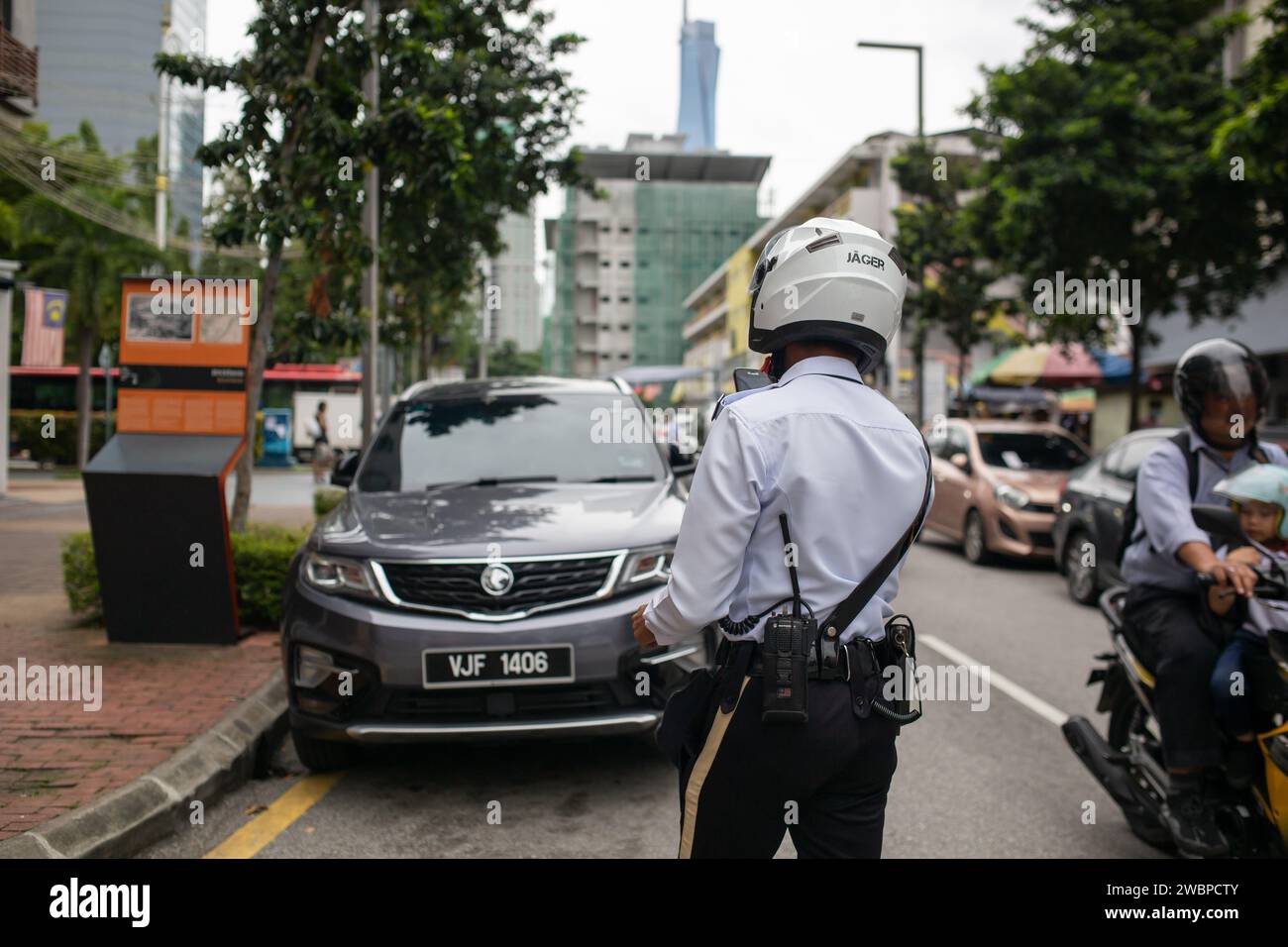 Kuala Lumpur, Malesia - 8 gennaio 2024: Agente della polizia stradale che fotografa ed emette biglietti per i proprietari di veicoli parcheggiati illegalmente. Foto Stock