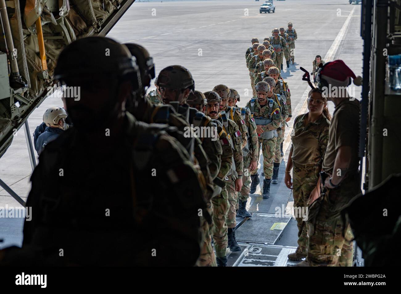 Gli operatori delle forze speciali congiunte del Qatar si imbarcano su un C-130J Super Hercules, assegnato al 61st Expeditionary Airlift Squadron, durante l'operazione Desert Redhawk 2 in una posizione non rivelata nell'area di responsabilità del comando centrale degli Stati Uniti il 25 dicembre 2023. Le ripetute operazioni di addestramento in volo e in volo congiunte con i paracadutisti dell'esercito degli Stati Uniti e le forze speciali congiunte del Qatar costruiscono relazioni tra queste comunità e consentono l'addestramento incrociato sulle specifiche della missione tra le forze. (Foto U.S. Air Force del sergente dello staff Caleb Roland) Foto Stock