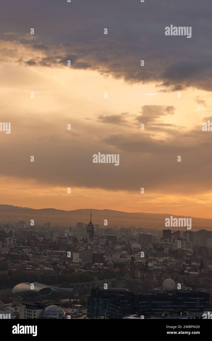 Una vista panoramica di Tbilisi circondata da maestose montagne in lontananza all'alba in Georgia Foto Stock