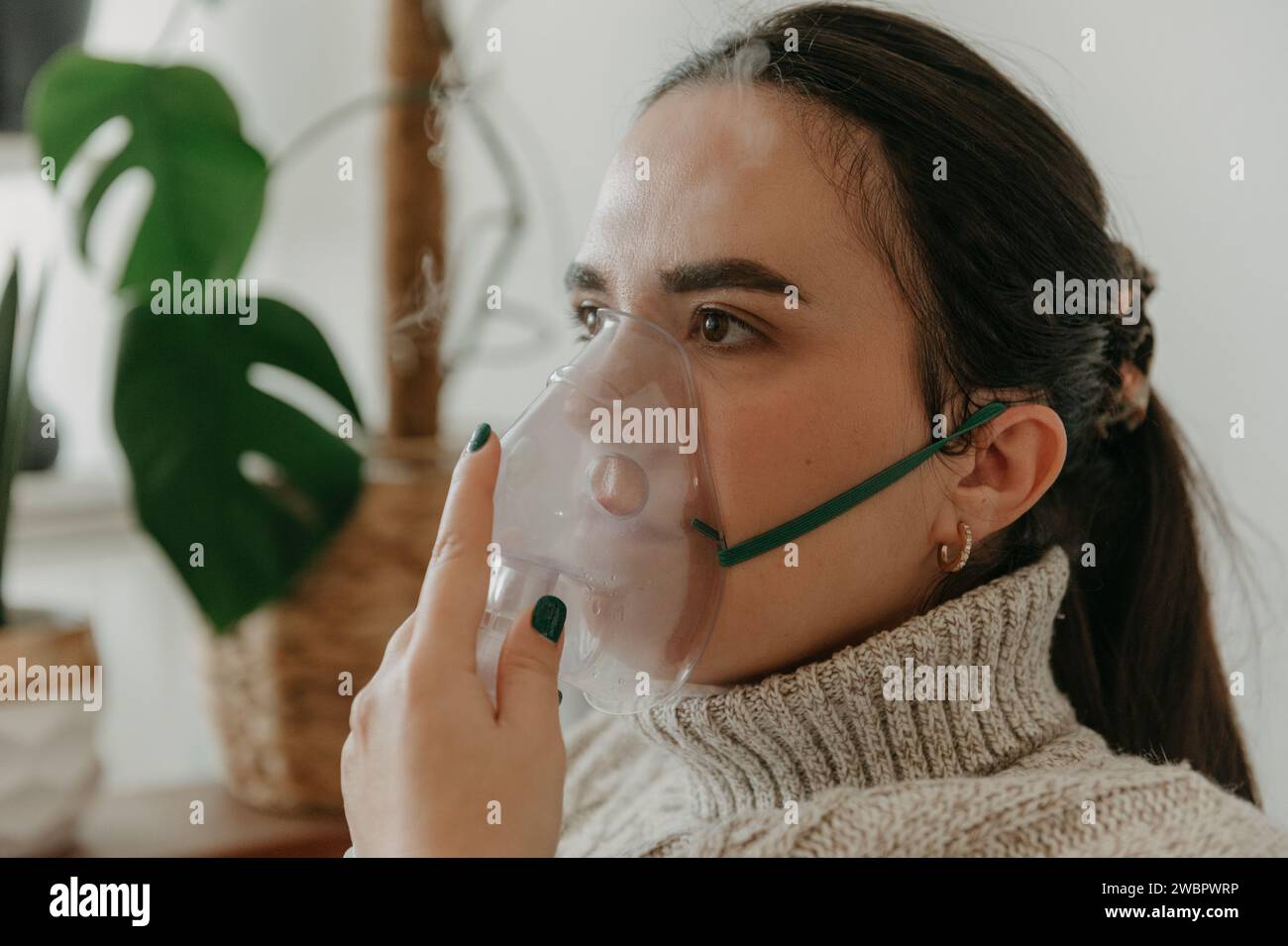 Una giovane donna che indossa una maschera respiratoria per facilitare una respirazione corretta Foto Stock