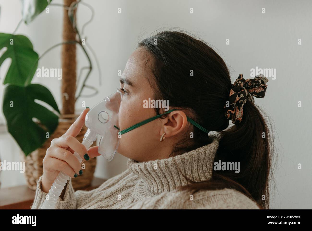 Una giovane donna che indossa una maschera respiratoria per facilitare una respirazione corretta Foto Stock