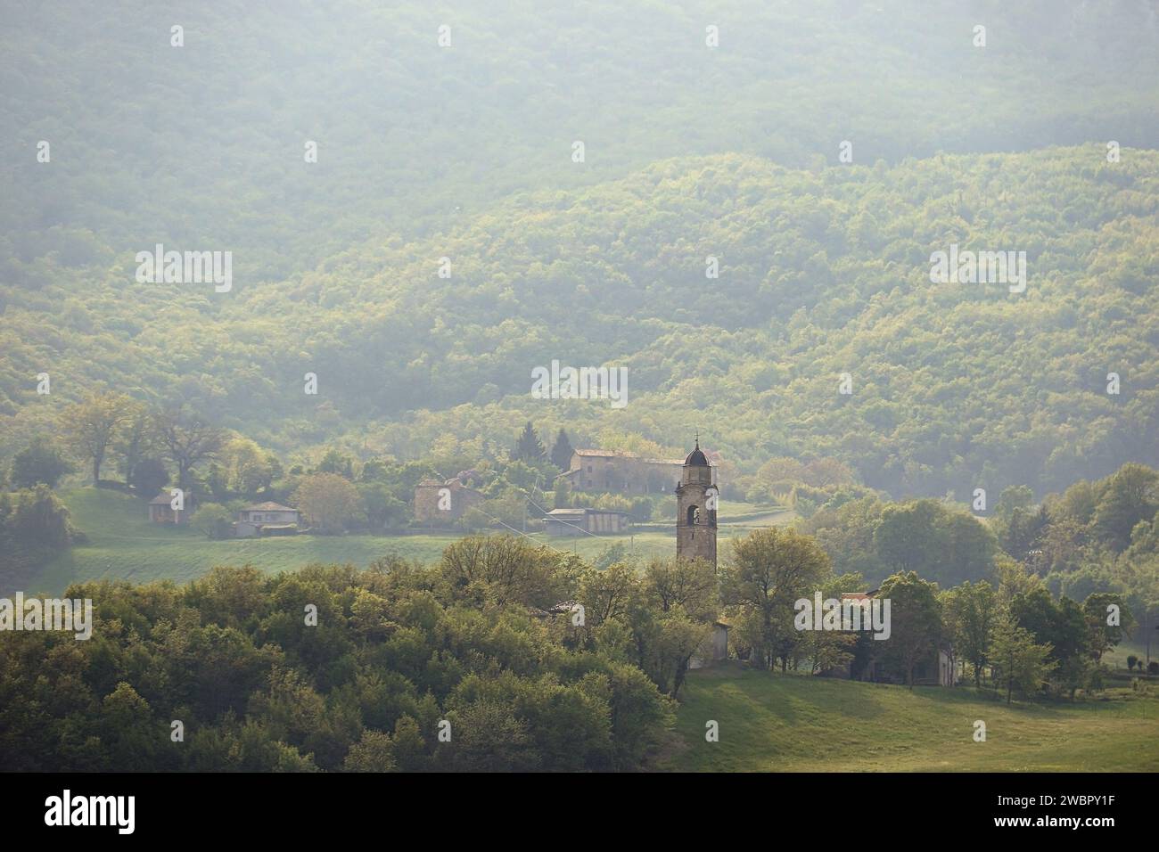 Una scena naturalistica italiana con un villaggio e il campanile della chiesa immerso nel verde lussureggiante. Foto Stock