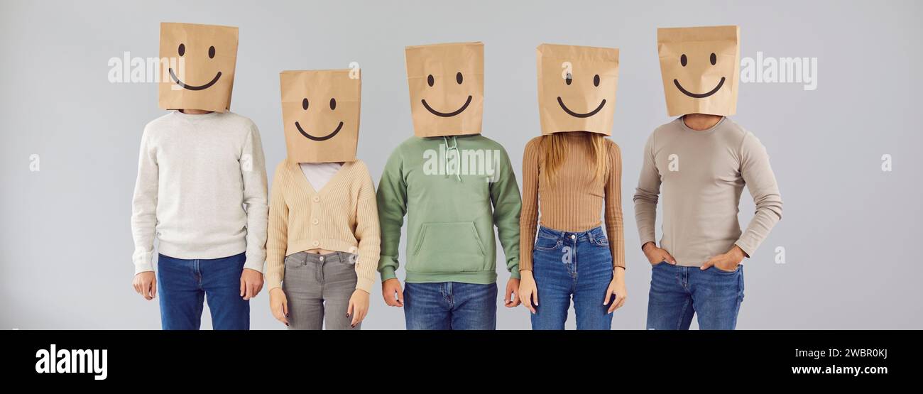 Gruppo di uomini e donne che indossano sacchetti di carta per la spesa sorridenti sulla testa Foto Stock
